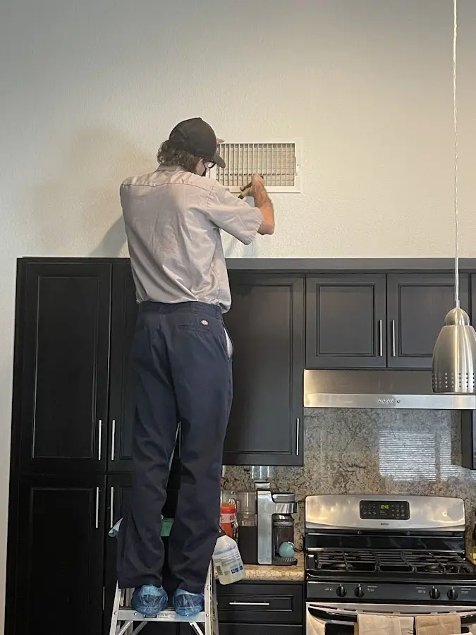 Technician inspecting an air vent during HVAC service in South Windsor